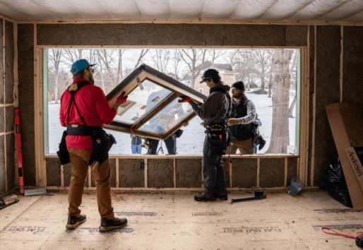 A construction crew install a window into a very large rough opening.