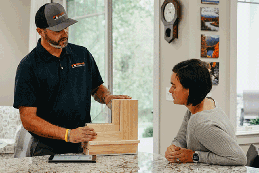 A contractor shows a customer a window corner section.