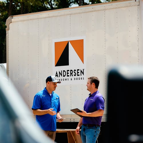 Two men chatting in front of an Andersen Windows truck