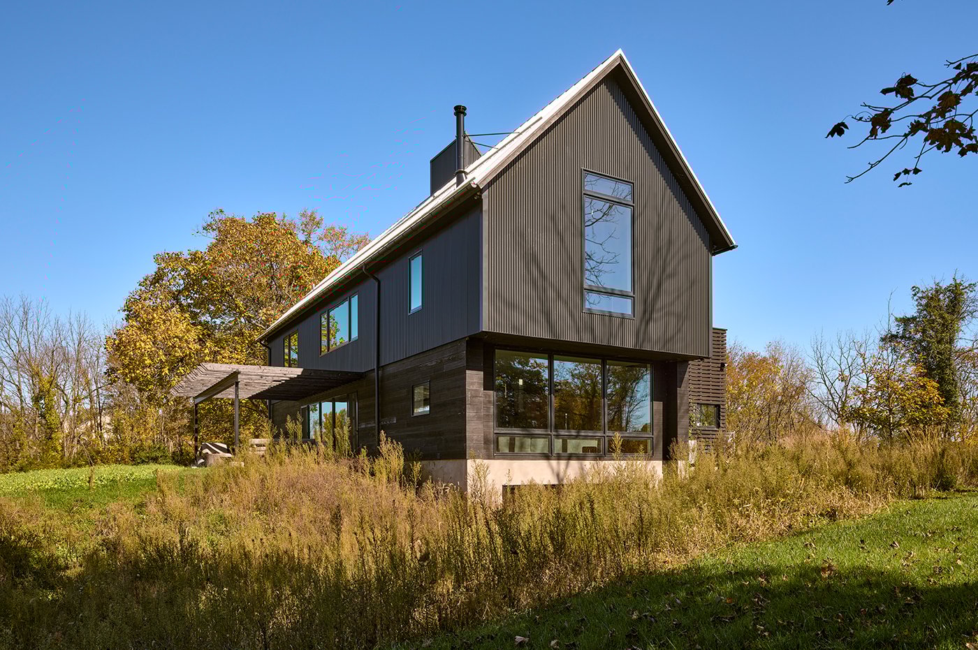 A black barn-shaped home with very large Andersen® E-Series Picture Windows and E-Series Awning Windows.