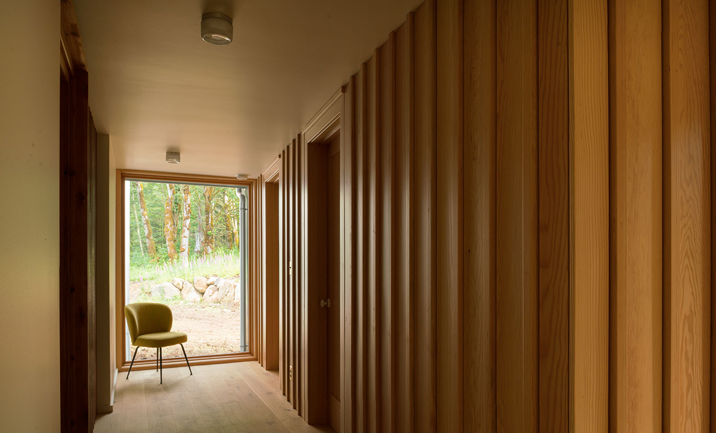 A wood paneled hallway that ends in a floor-to-ceiling picture window.