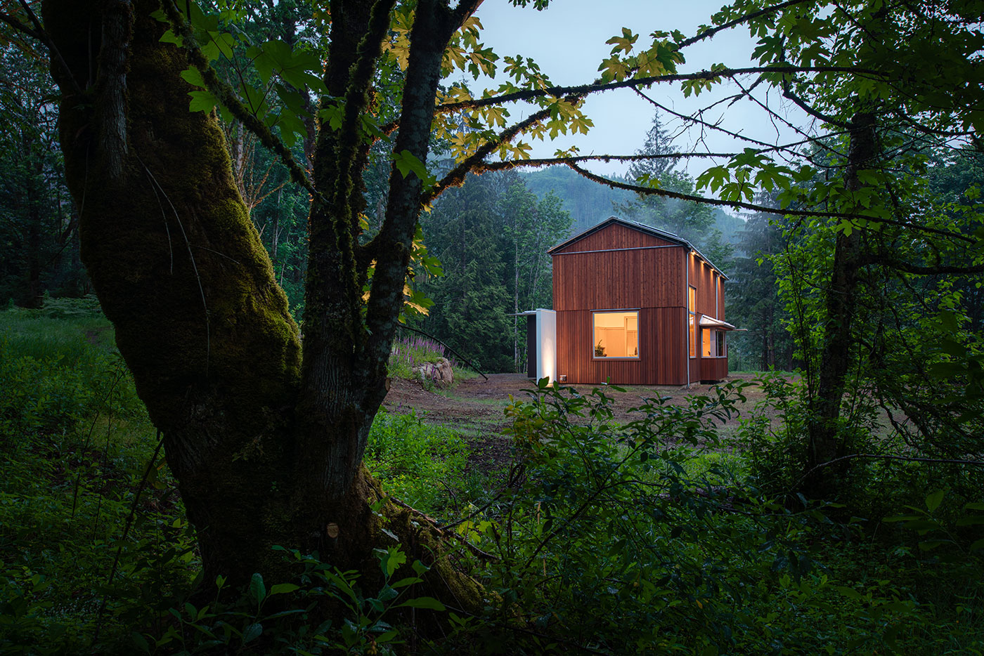 An exterior shot of a barn-shaped home with vertical cedar cladding and large windows.
