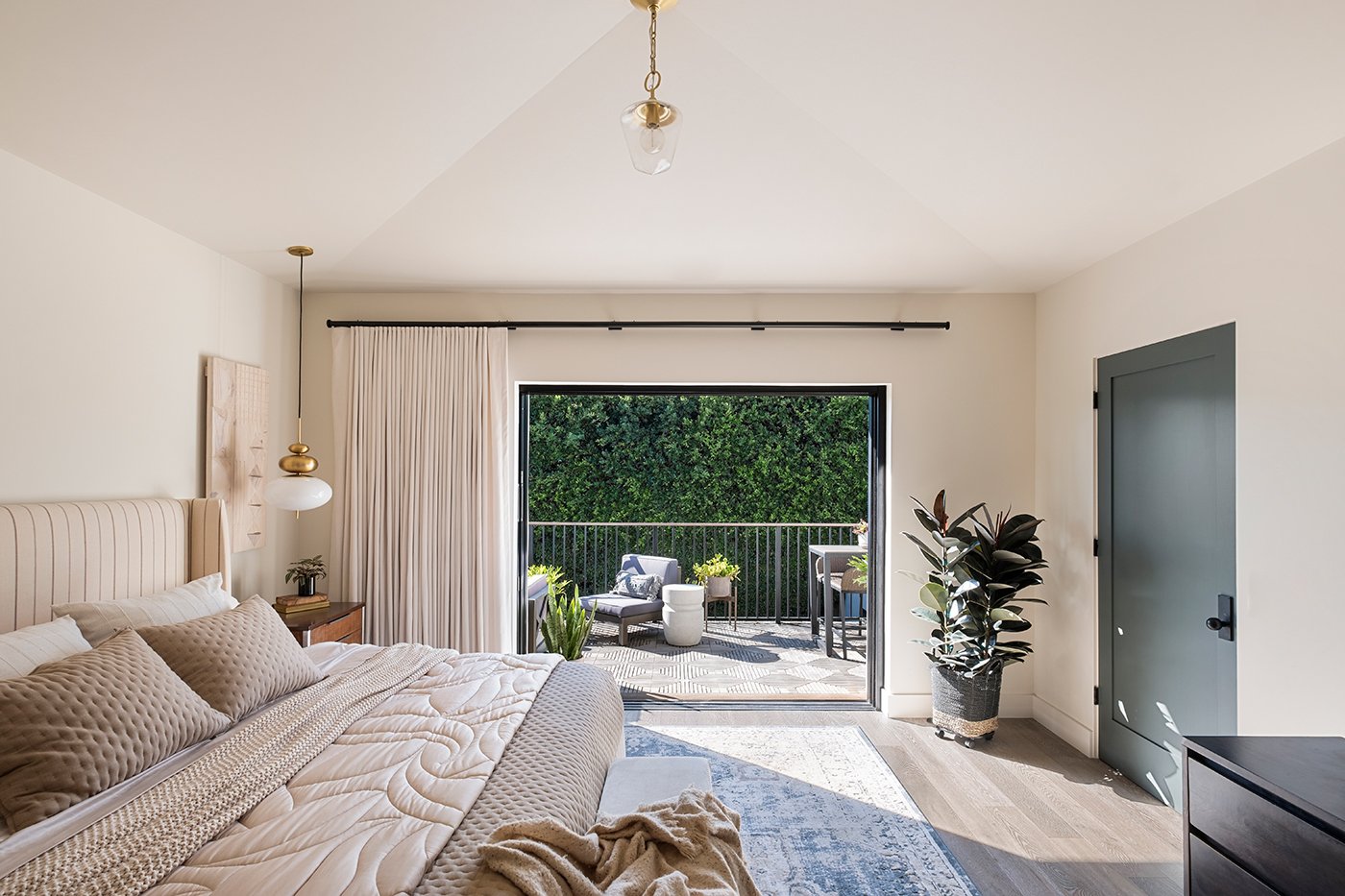 A bedroom with a pocketing MultiGlide Door open to the sunny balcony outside.