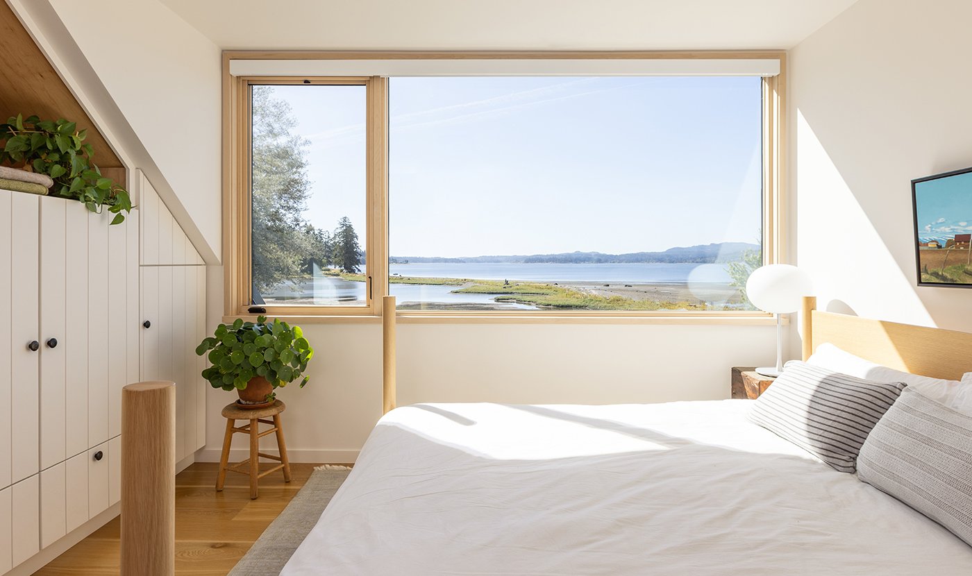 A bedroom with a large window combination composed of an Andersen E-Series Casement Window and E-Series Picture Window.