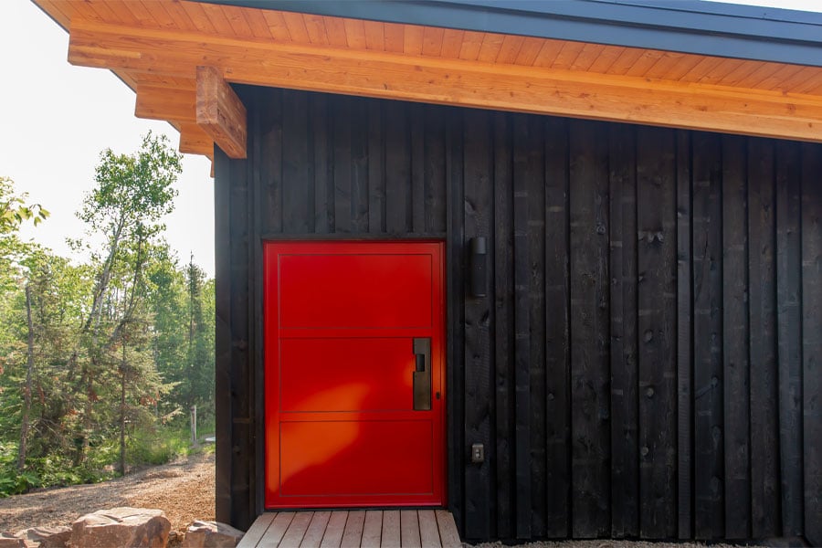 Red entry door on black house