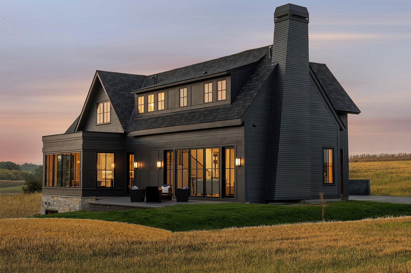 A black farmhouse in a prairie setting.