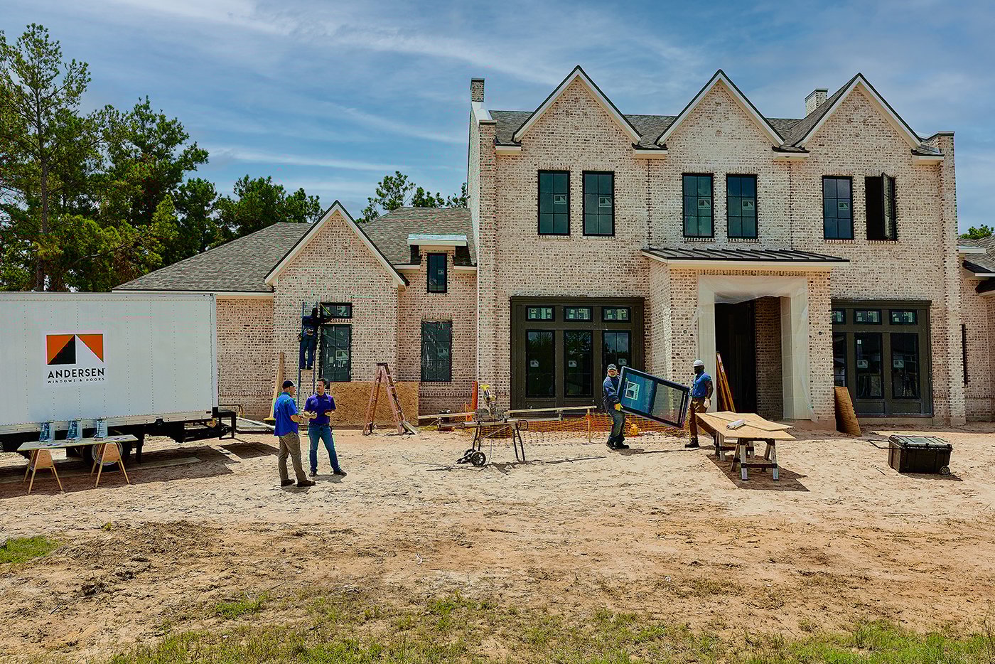 A new construction home with a brick facade where black Andersenn windows are being installed.