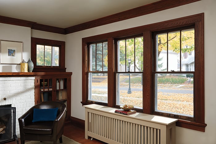 A living room with vinyl replacement windows on the left and with Andersen Woodwright Double-Hung Windows on the right.