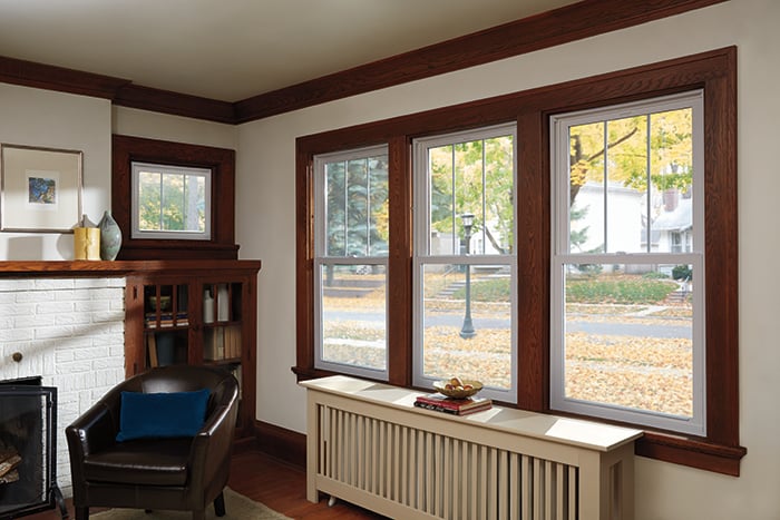 A living room with vinyl replacement windows on the left and with Andersen Woodwright Double-Hung Windows on the right.