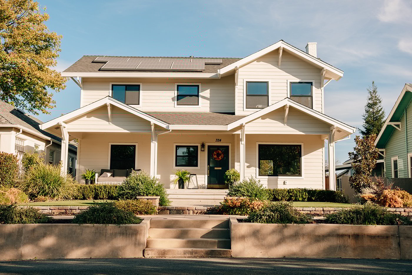 A white home with black replacement windows and solar panels on the roof.