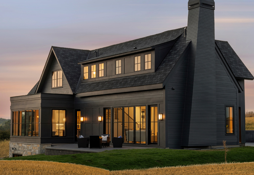 two story brown house with sunset in background showcasing andersen e series windows