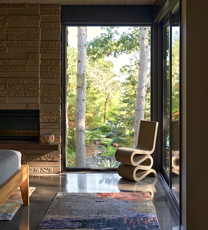A bedroom with polished concrete floors, a fireplace, and floor-to-ceiling glass.