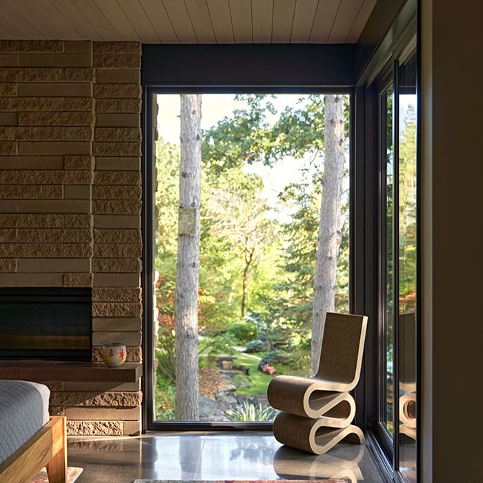 A bedroom with polished concrete floors, a fireplace, and floor-to-ceiling glass.