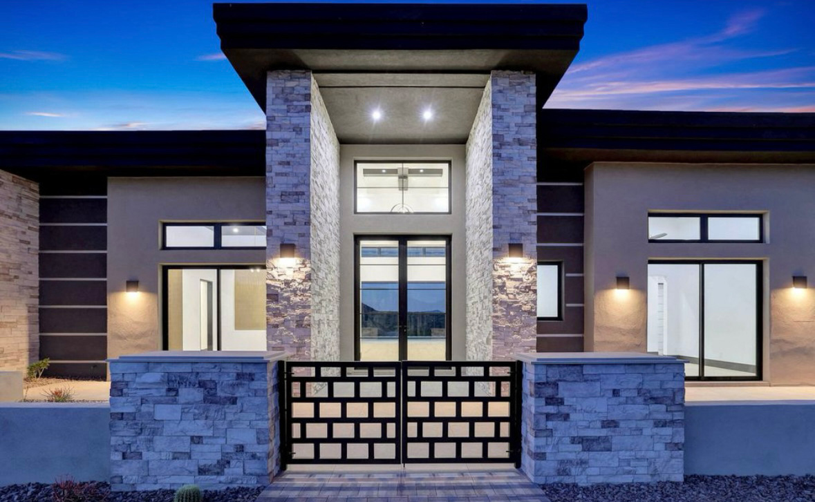 Close-up rendering of a contemporary luxury home entrance in the desert with large, black Andersen® 100 Series Picture Windows on each side. 