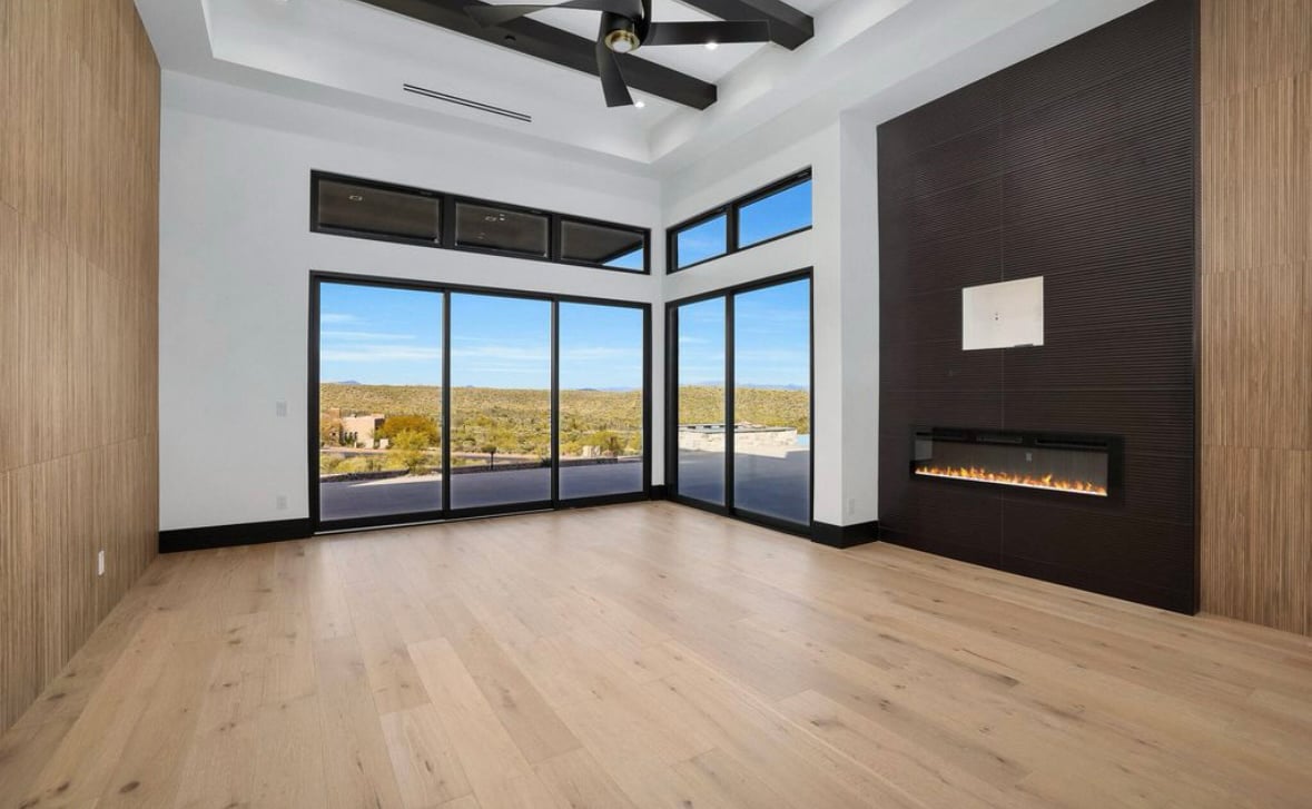 Interior rendering of a contemporary luxury home in the desert with a wall of large, black Andersen® 100 Series Picture Windows providing unobstructed views of the landscape beyond. 