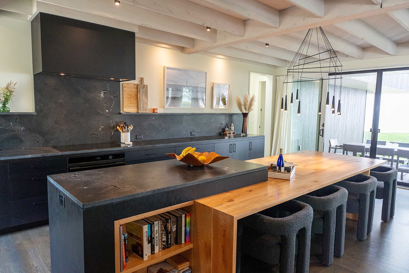 A kitchen with dark countertops and a wooden bar with gliding patio doors. 