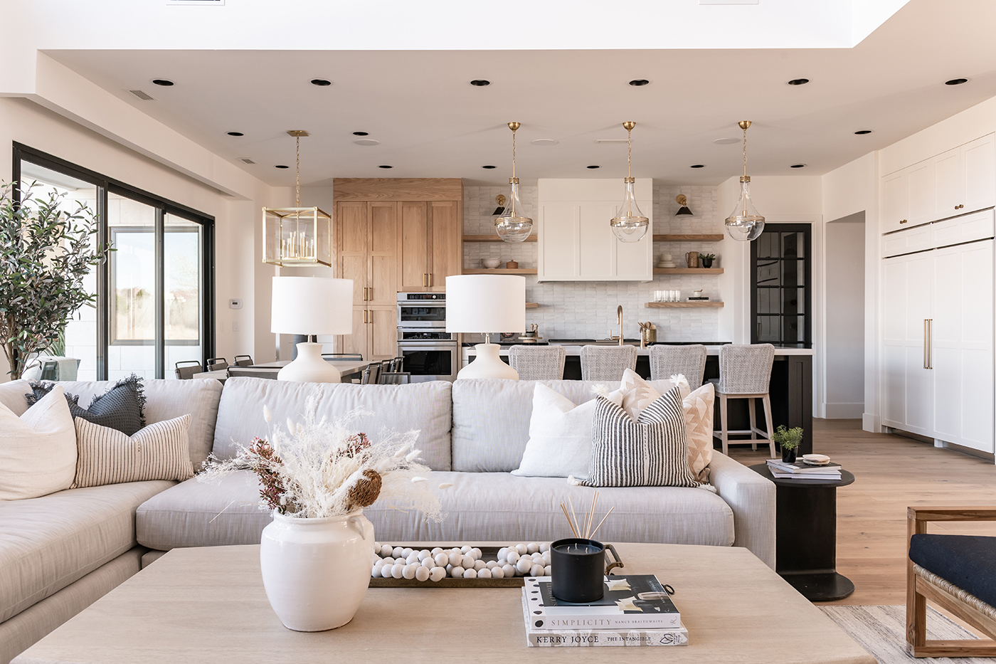 Kitchen and living room with a coastal contemporary look and feel with cool neutrals, natural wood, and modern black windows.  