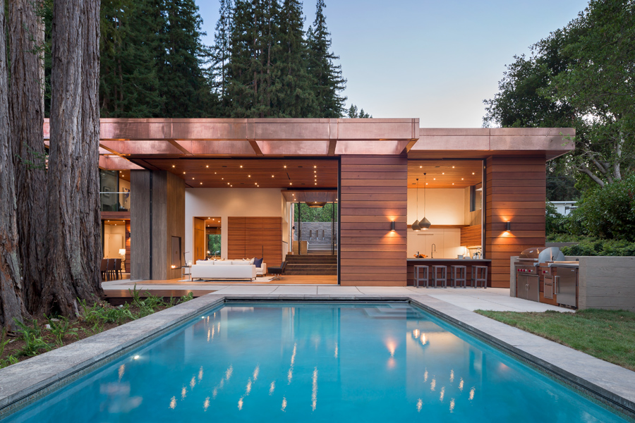 A modern home surrounded by nature and a 14-foot-tall Andersen® Liftslide Door that opens up the entire front-facing wall to the outdoor landscape and pool.