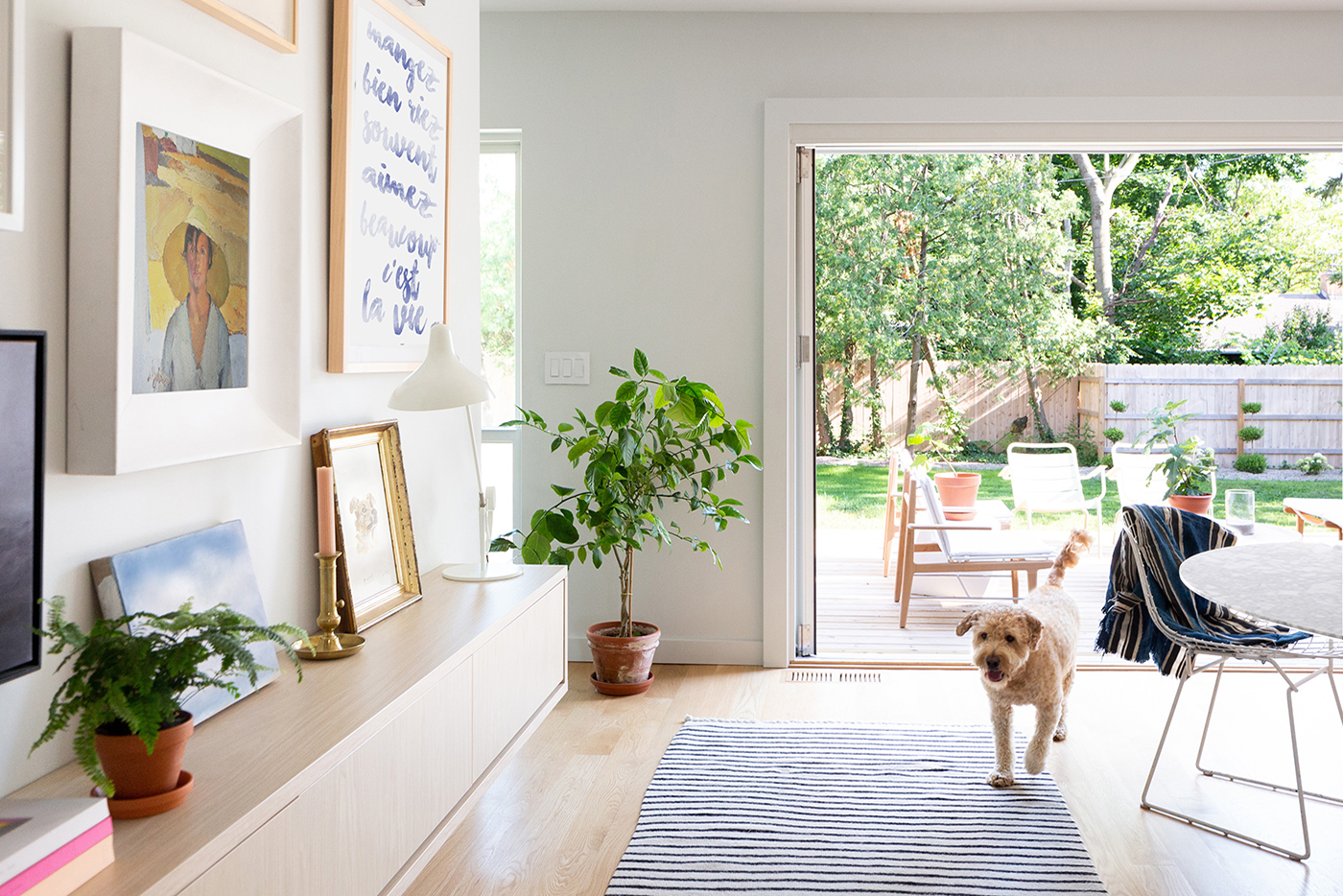 A coastal interior room with an Andersen® Folding Outswing Door opening a wall to the sunny outdoors. 