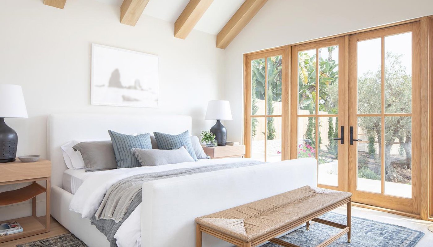 An airy bedroom with high ceilings and a four-panel E-Series Hinged Patio Door.