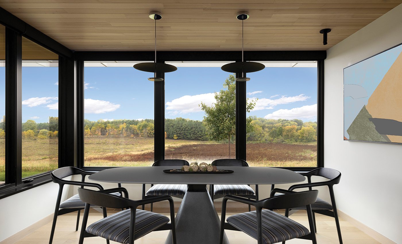 A dining table and chairs in a space where two walls are completely filled with Andersen E-Series Casement Windows.