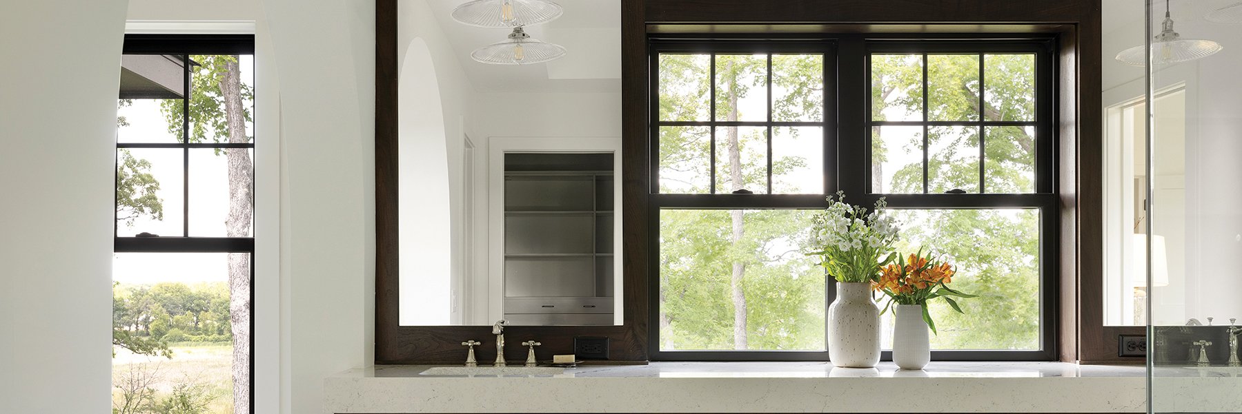 A bathroom with Andersen® 100 Series Single-Hung Windows in between the sinks.