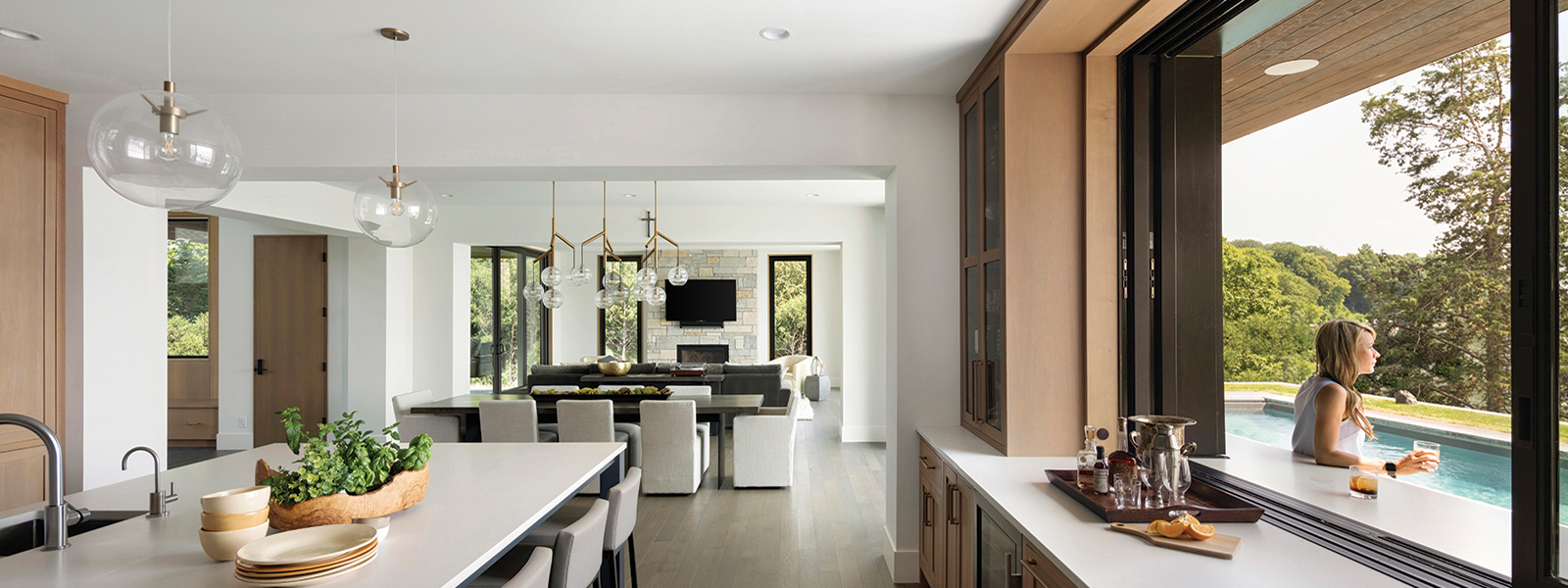 A woman sits outside an open Andersen® MultiGlide™ Pass-Through Window.