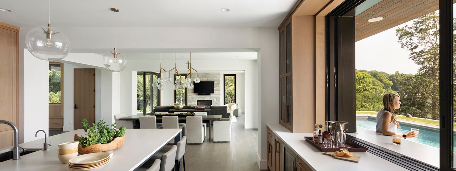 A woman sits outside an open Andersen® MultiGlide™ Pass-Through Window.