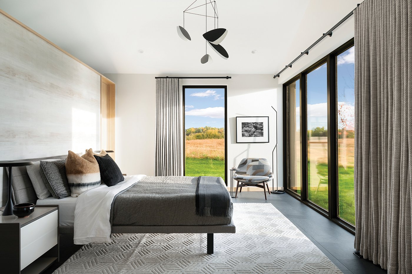 A bedroom with a whole wall of Andersen E-Series Picture Windows that overlook a prairie