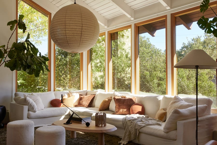 A dining room with floor-to-ceiling Andersen E-Series Windows with white oak frames that wrap around a corner.