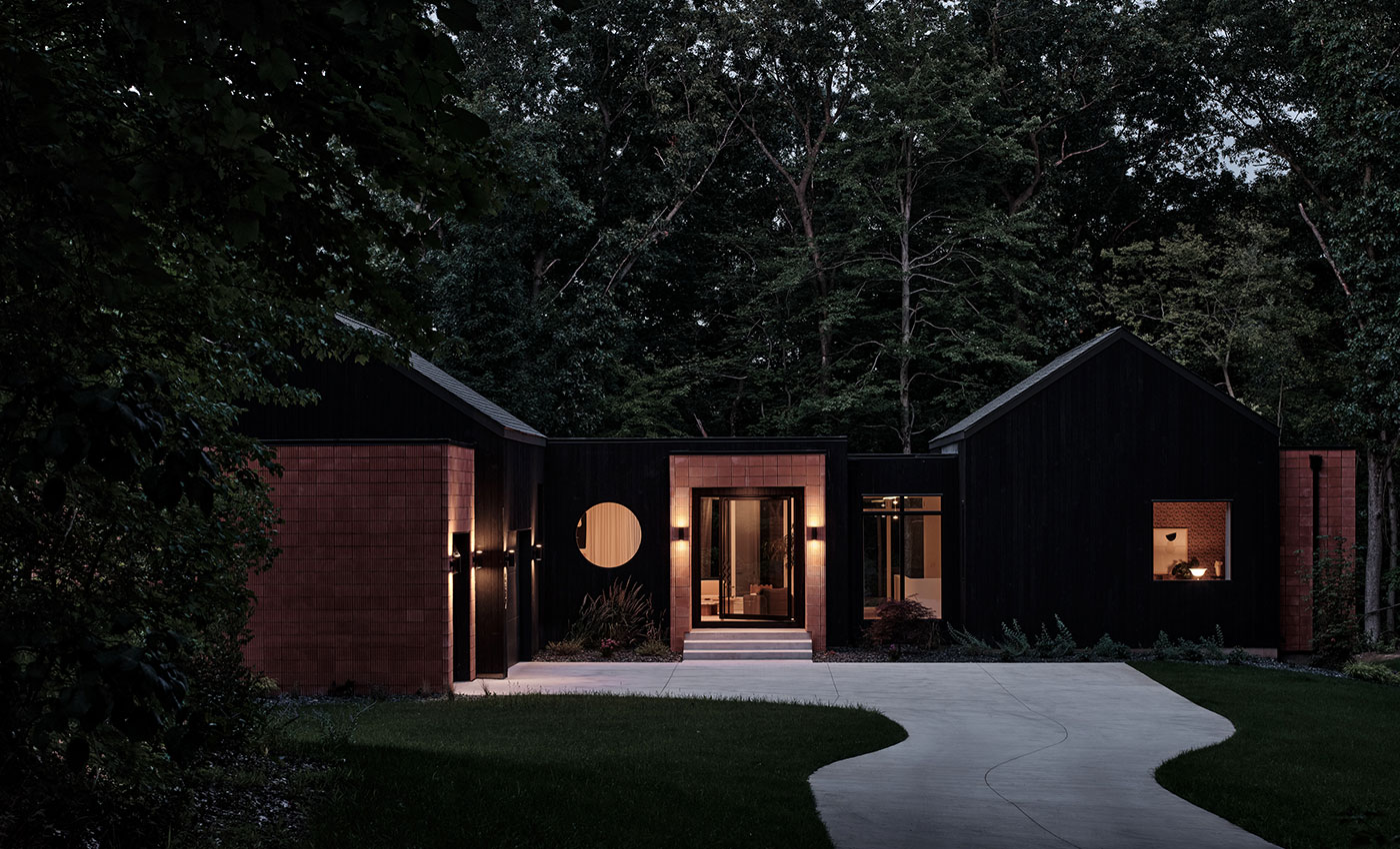 A black home with brick accents and a prominent Andersen® E-Series Specialty Window in the shape of a circle.