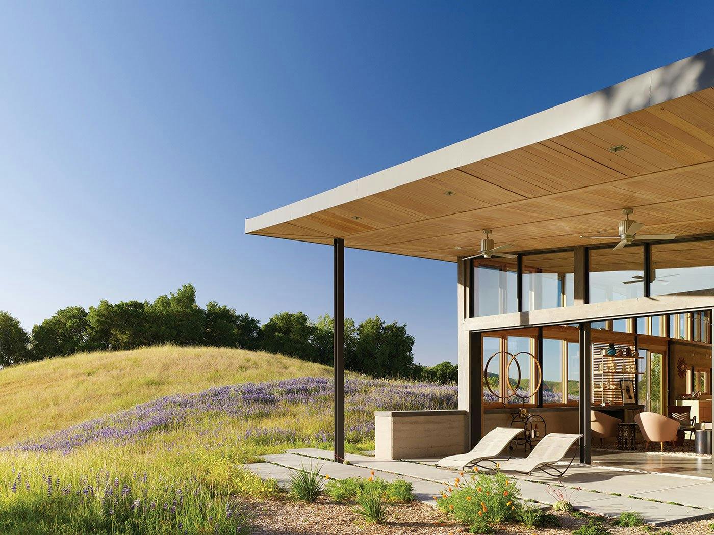 A hilltop ranch home with a large overhang covering a patio that’s connected to the home through large Liftslide Doors.