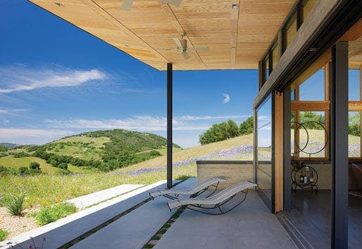 A roof overhang shading a patio with rolling tree-covered hills in the background.