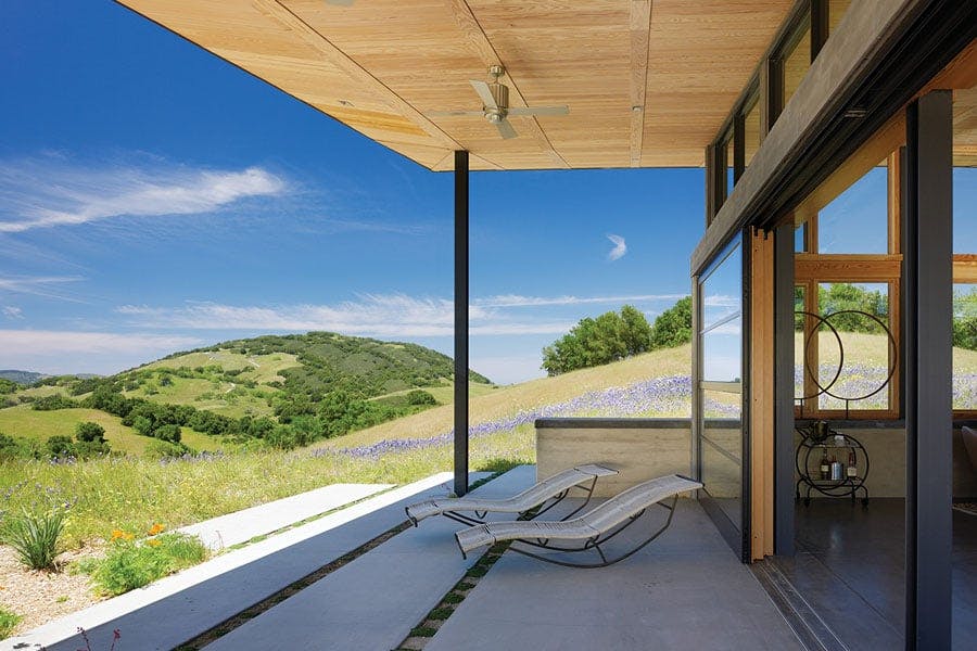 A roof overhang shading a patio with rolling tree-covered hills in the background.