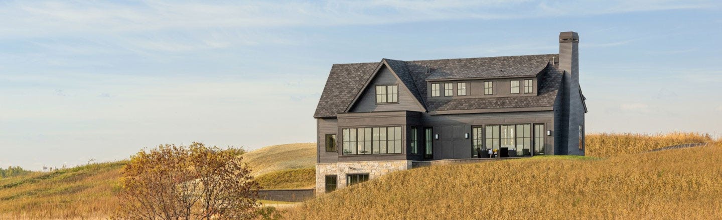 gray two story house in the middle of wheat field