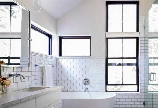 Modern white bathroom with tiled walls and single-hung windows.