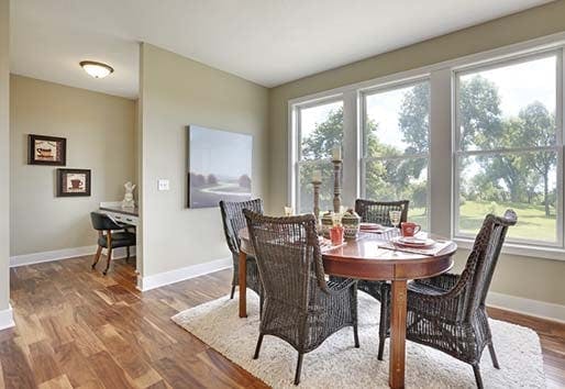 Neutral dining room with table set in front of white Andersen 200 series double-hung windows.