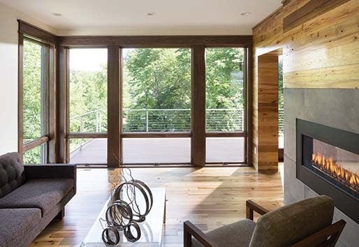 Living room with wood walls, flooring, and an Andersen 400 series patio door